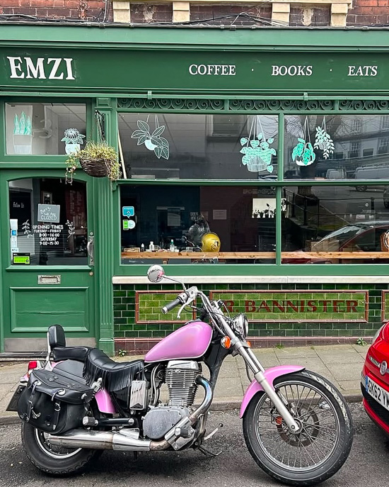 An image showing the shop front of Emzi, a cafe in Clifton, Bristol. A pink motorbike is parked outside.
