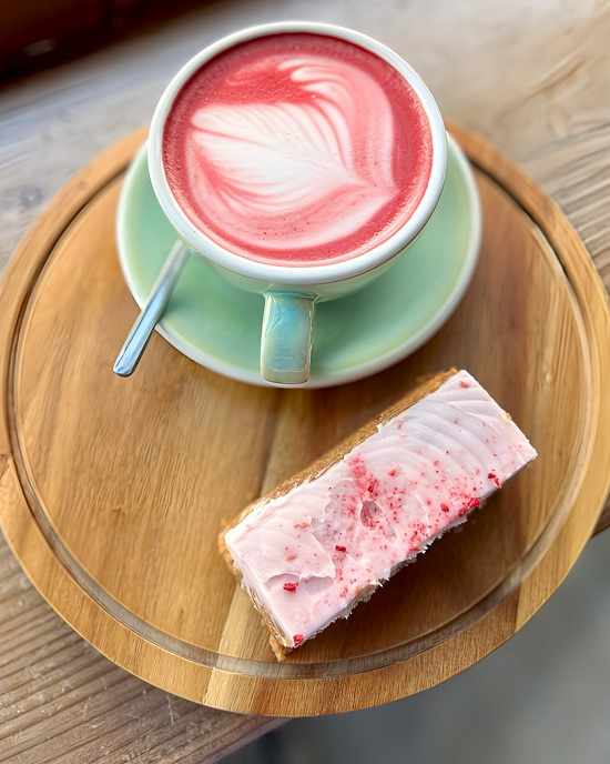 An image showing a a pink coloured latte art and a pink cake that is served at Emzi.